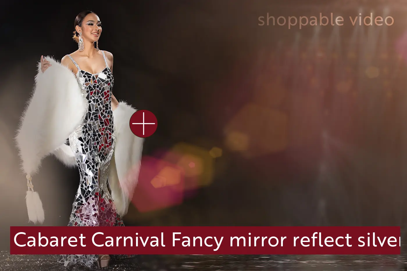 Frame from a shoppable video: a model in a mirrored silver gown with a clickable plus-marker hotspot and an on-screen product label